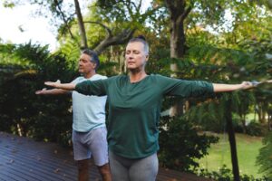 Happy Senior Caucasian Couple Practicing Yoga Stretching in Sunny Garden